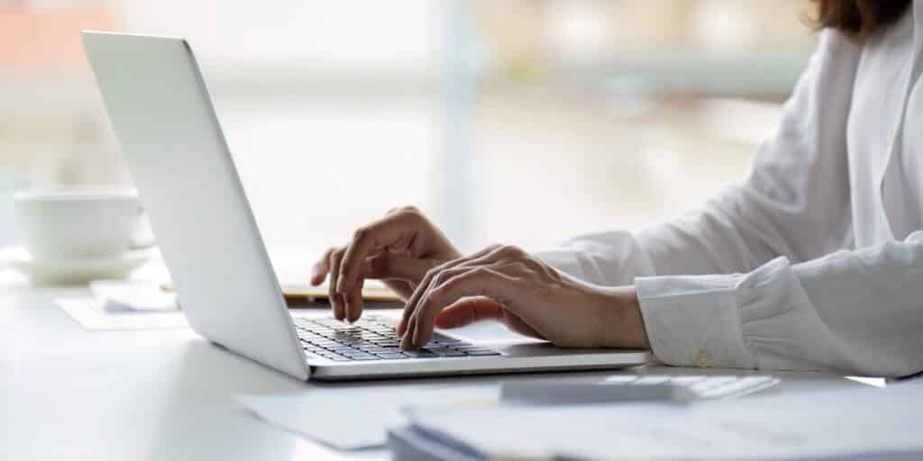 A person in office attire typing at a laptop